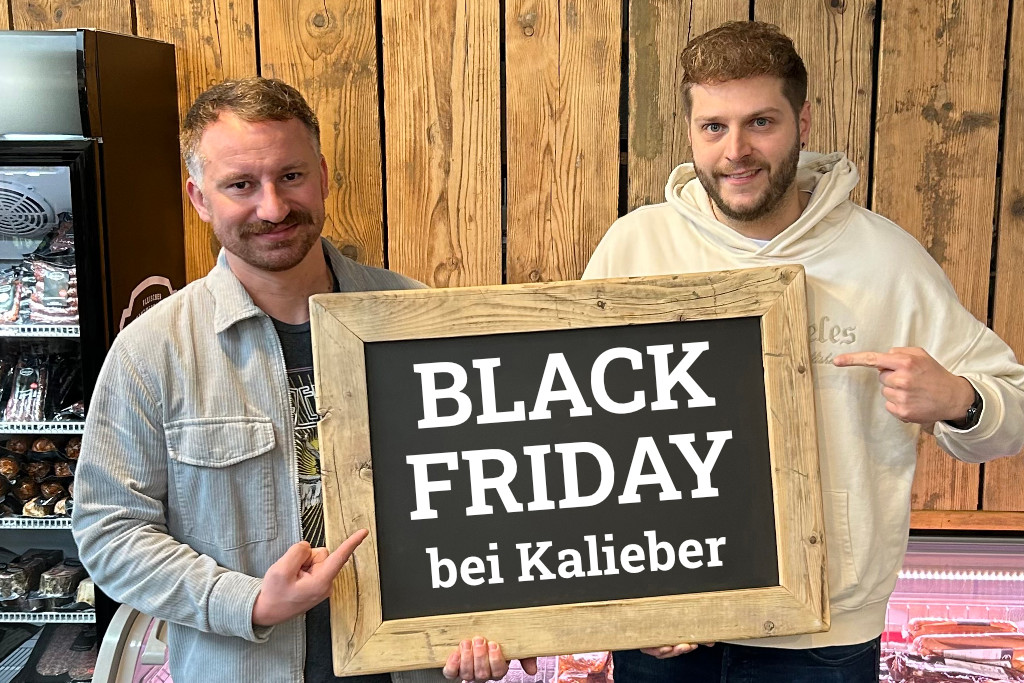 Zwei Kollegen bewerben mit einer Kreidetafel den Black Friday bei Kalieber
