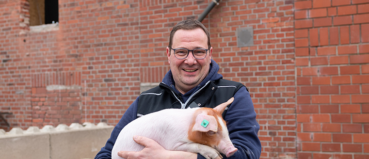 Landwirt Christian Holtmannspötter mit Ferkel auf dem Arm