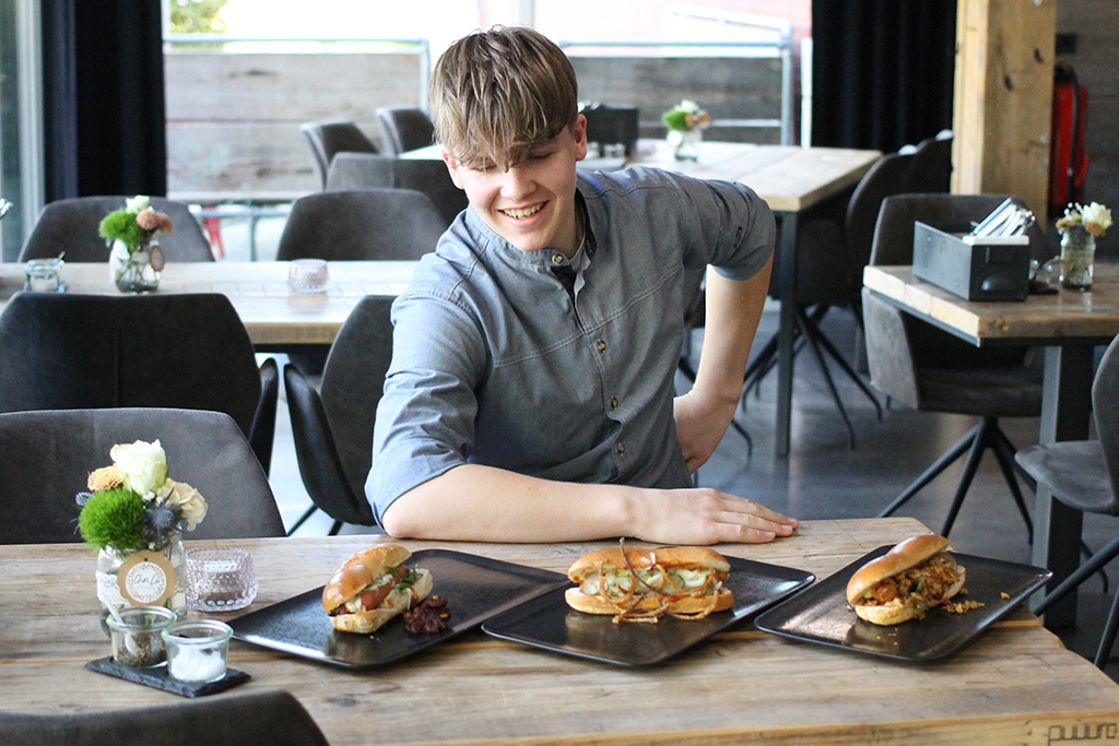 Azubi freut sich über drei angerichtete Hot-Dogs