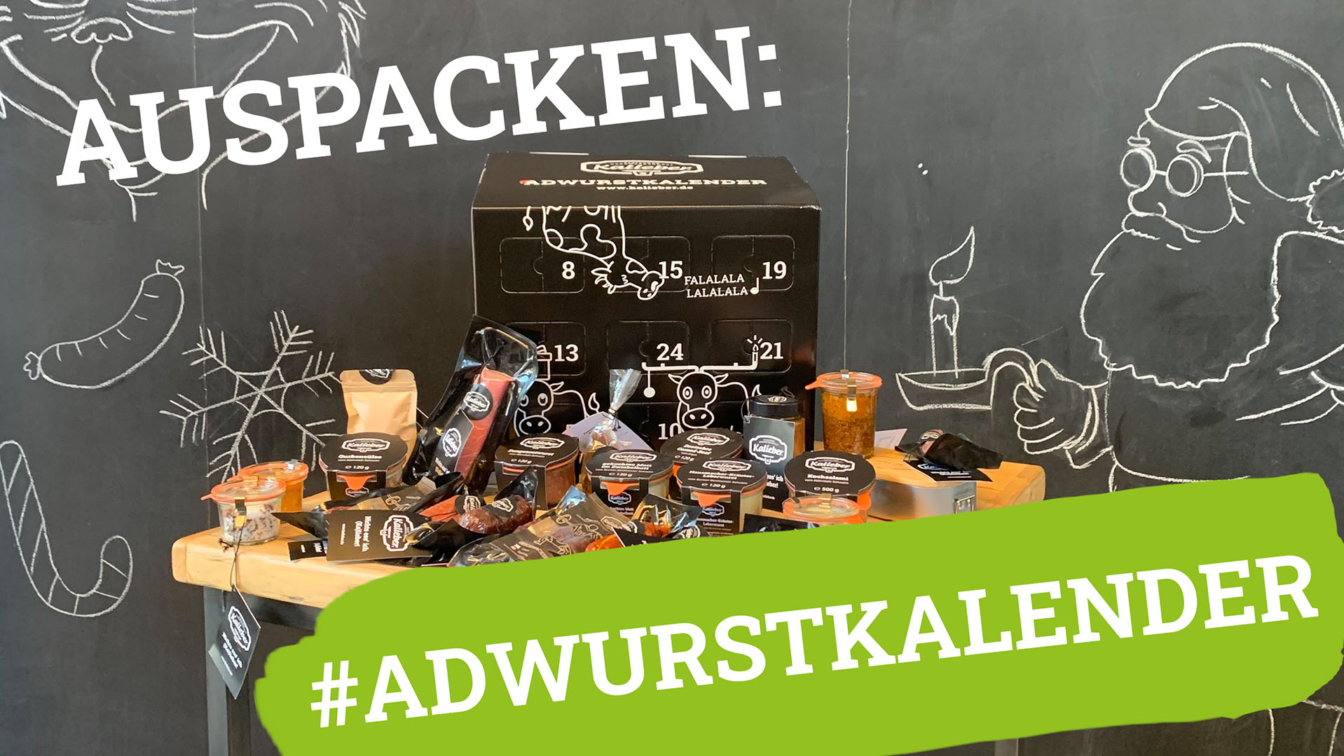 Kalieber ADWURSTKALENDER Inhalt des Adventskalenders 2021 auf einem Tisch, im Hintergrund weihnachtlich bemalte Tafel
