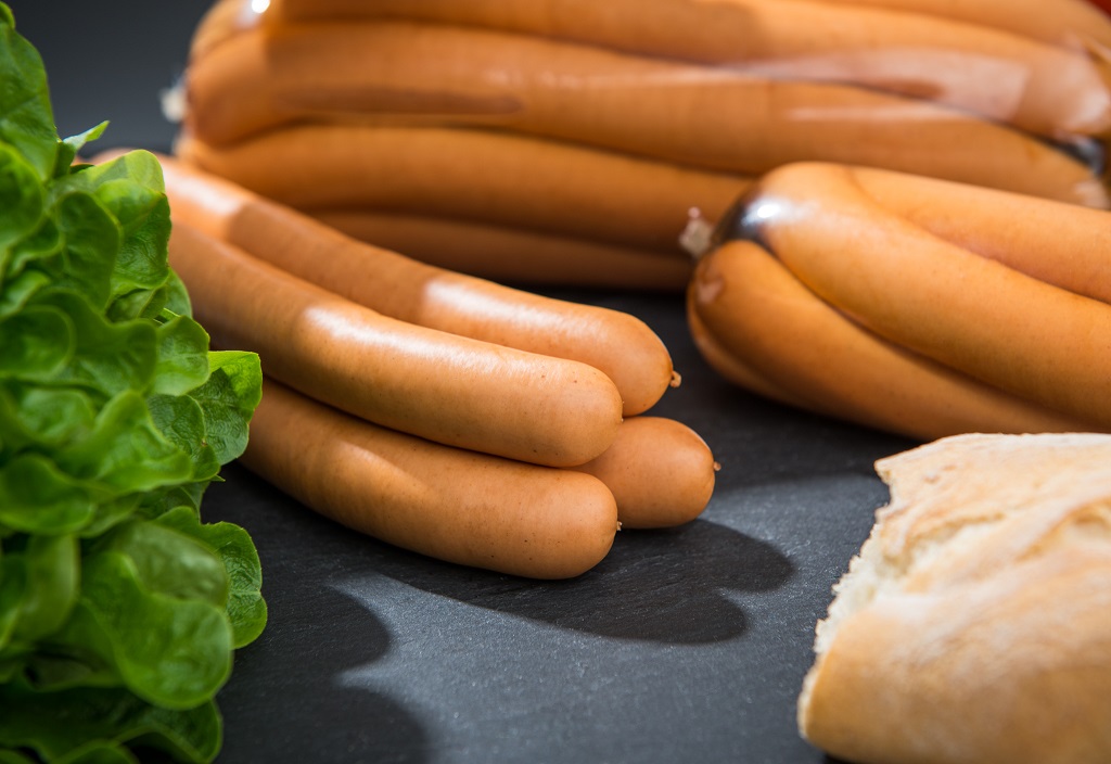 Wiener Würstchen vom Aktivstall-Schwein, 4er Pack  4 Wiener Würstchen, im Hintergrund weitere Packungen und Dekoration