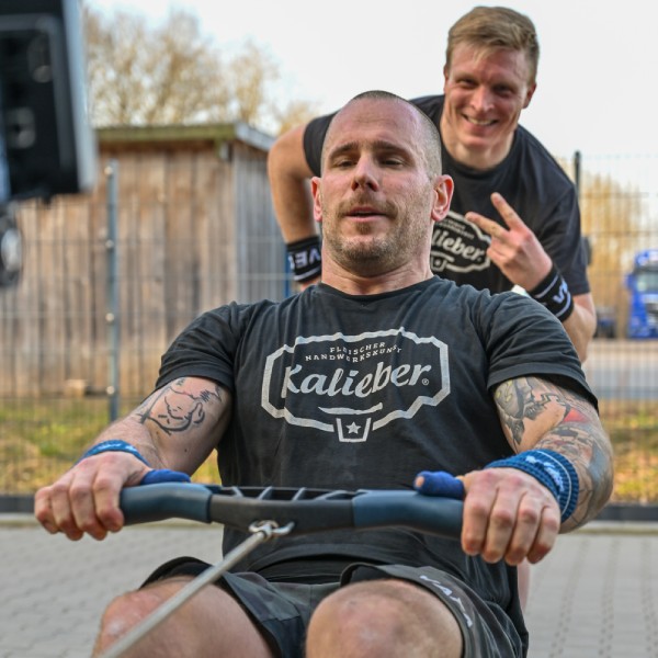 Mann im Vordergrund trainiert Mann im Hintergrund macht Peacezeichen mit Fingern