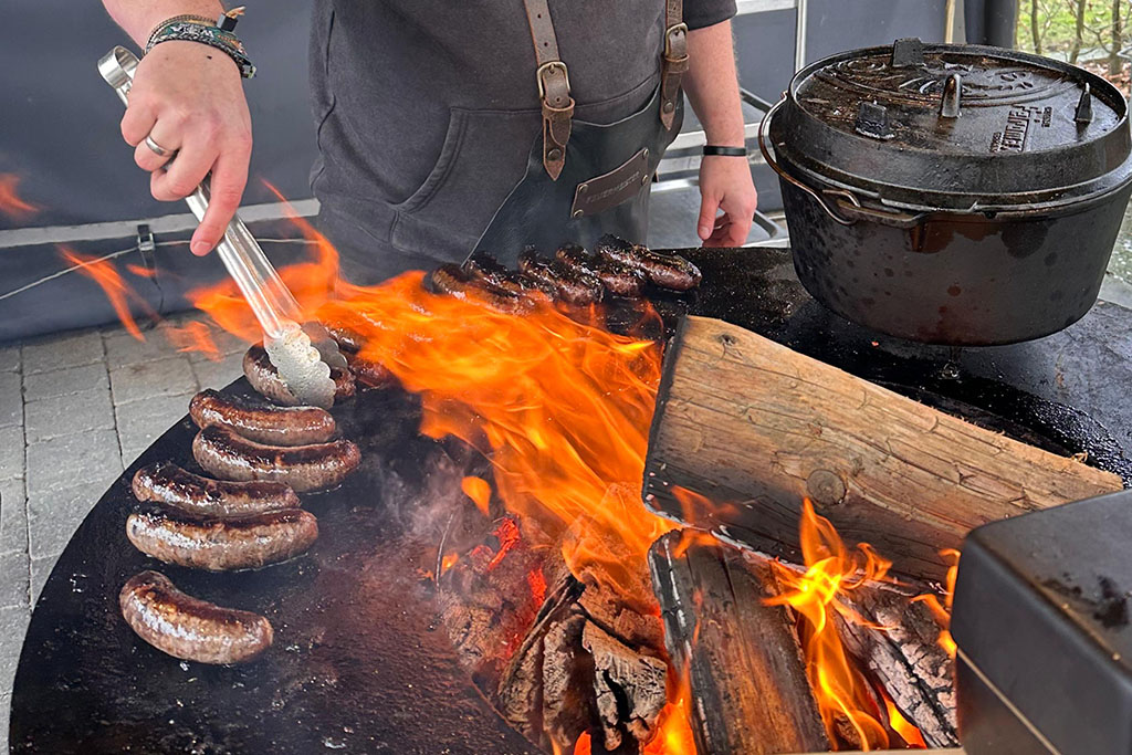 Wild-Bratwurst wird auf Feuerplatte gegrillt