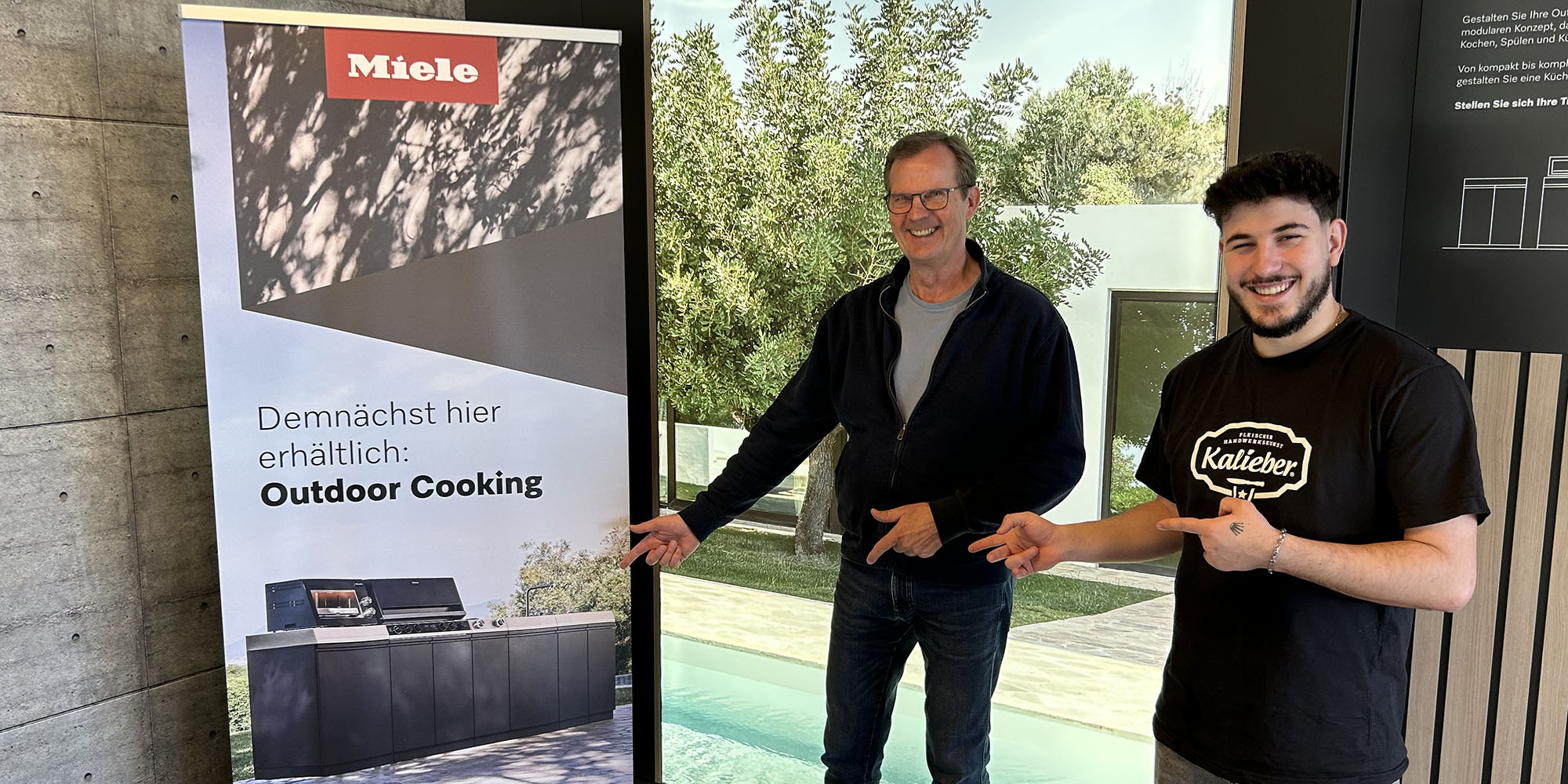 zwei Kalieber-Mitarbeiter präsentieren Miele-Werbung