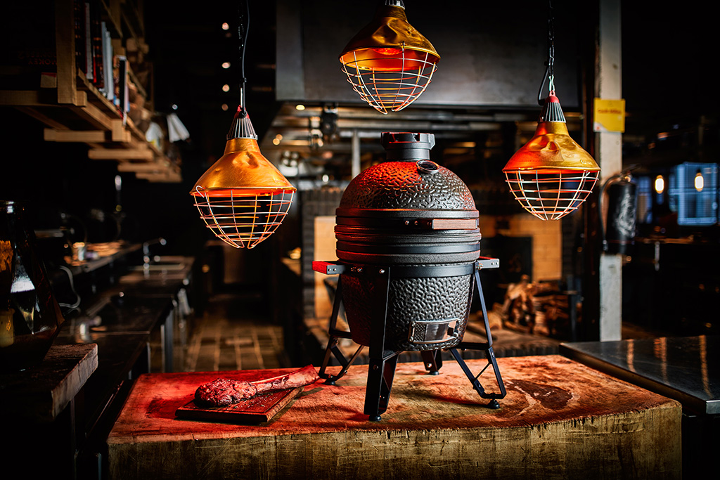 The Bastard Grill Grill in einer rustikalen Küche auf einem großen Holzblock