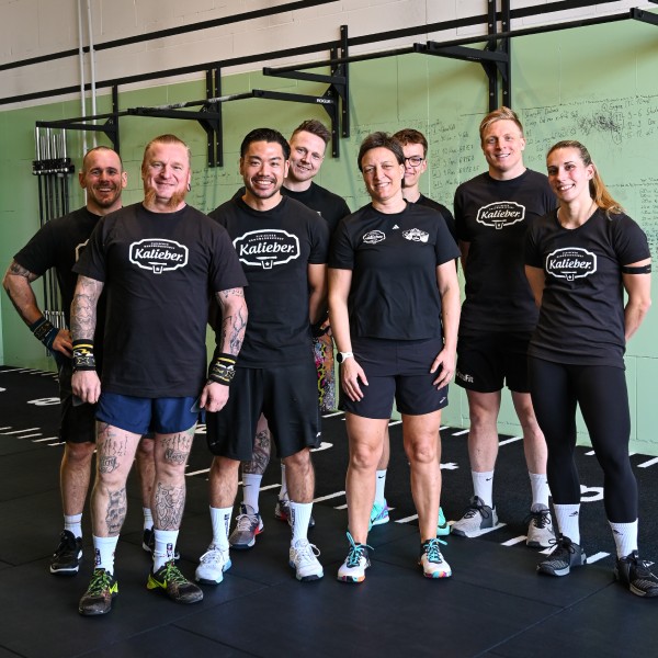 Kalieber Athleten Trainingstag 8 Frauen und Männer mit Kalieber T-Shirts im Fitnessstudio