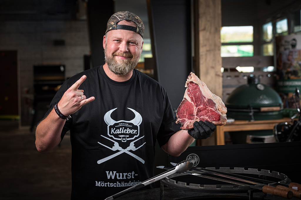 Kalieber-Mitarbeiter steht mit einem Dry Aged Steak in der Grillausstellung