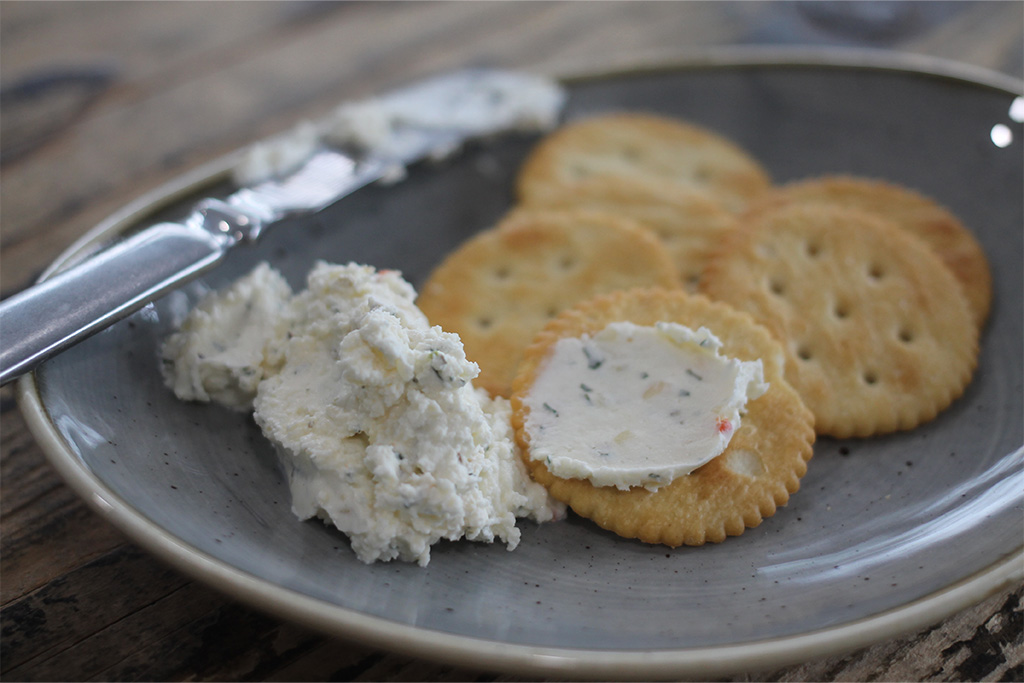 Dip auf Cracker auf Teller mit Messer