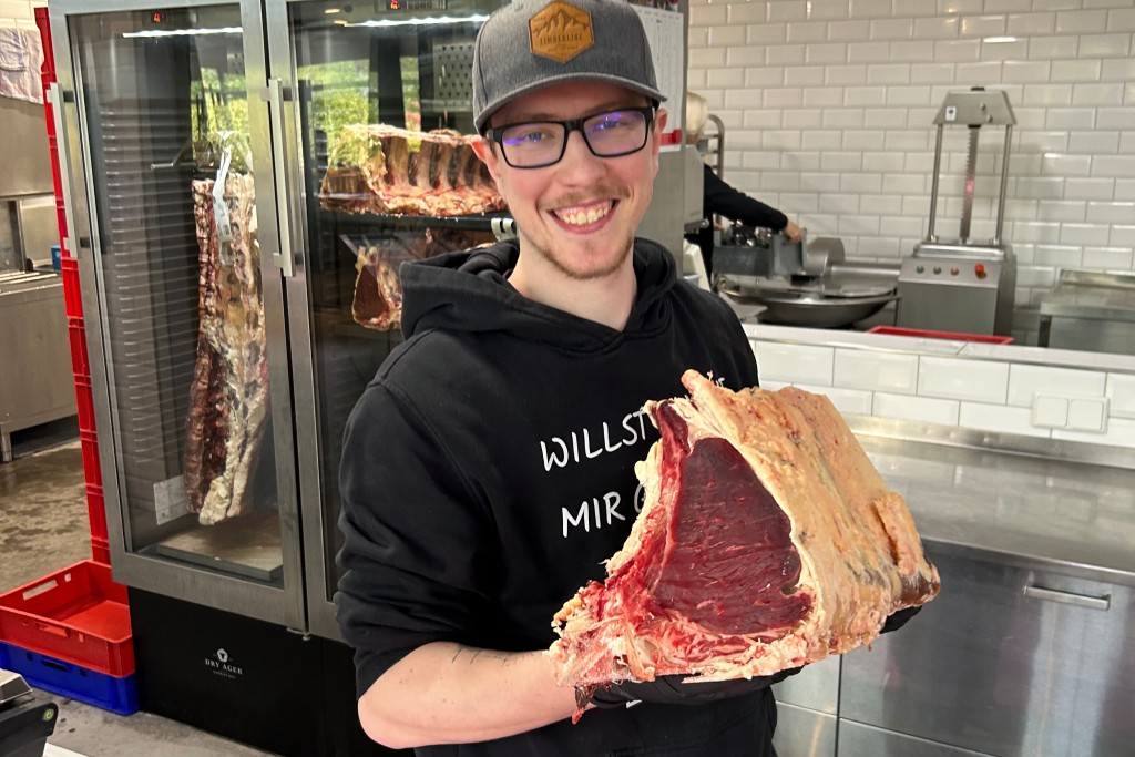 Junger Mann hält großes Rindersteak in den Händen