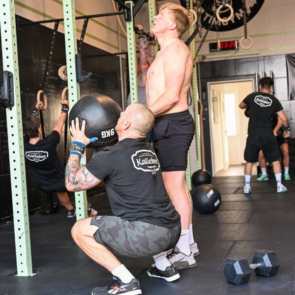 Functional Fitness Sponsoring Kalieber Zwei sportliche Männer im Fitnessstudio vor einem Gerät